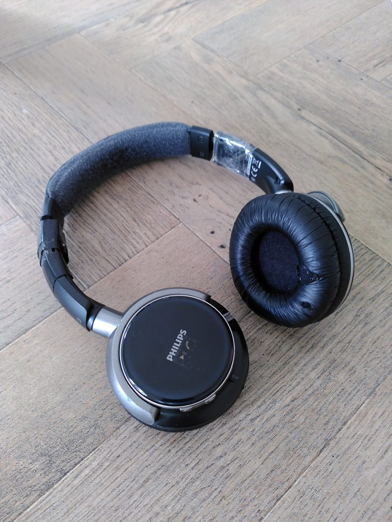 Photo of a pair of Philips Bluetooth headphones on a table, with tape around the edges to hold them together