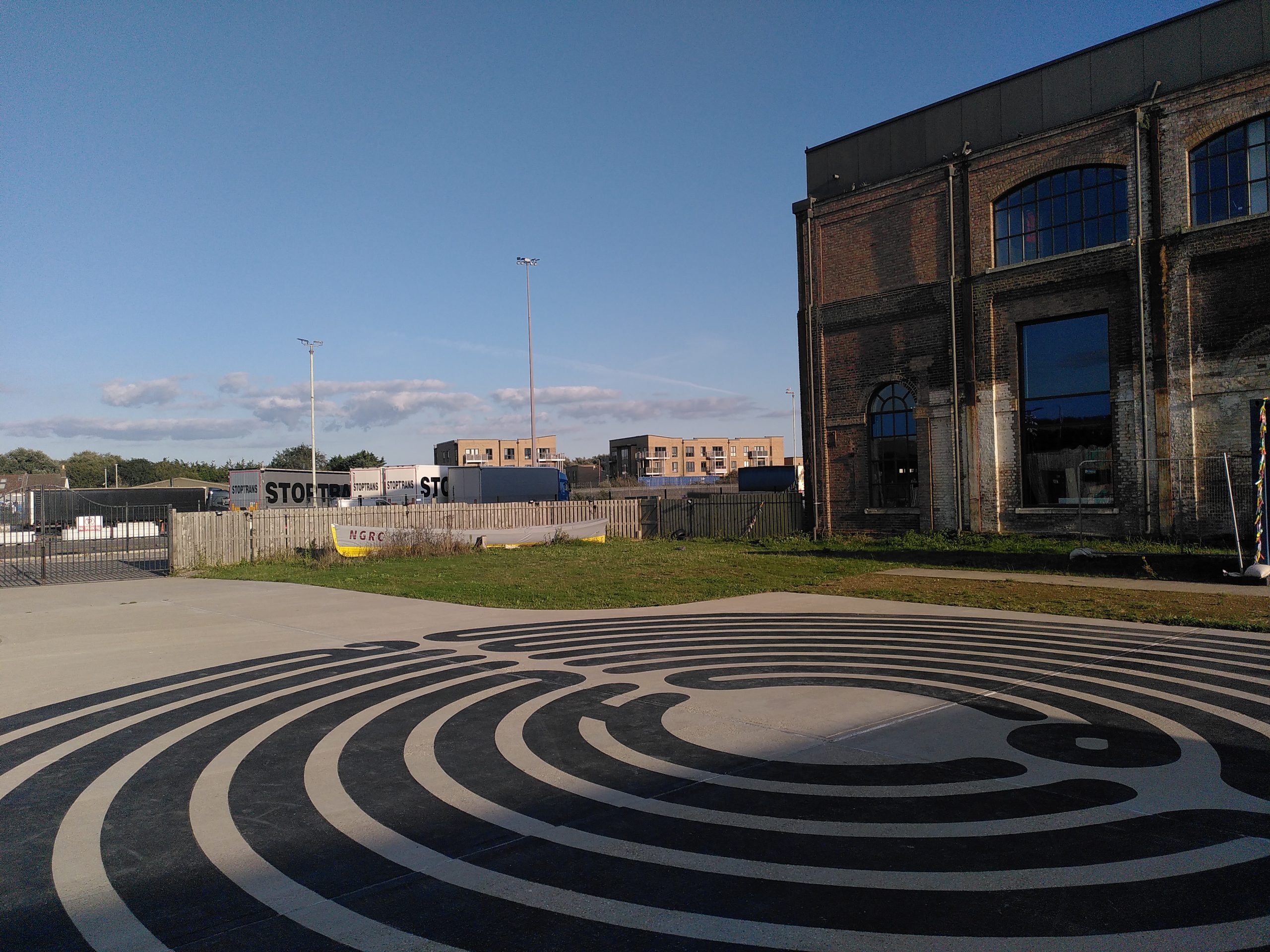 Photo of a circular labyrinth painted on the ground outside an old brick building.