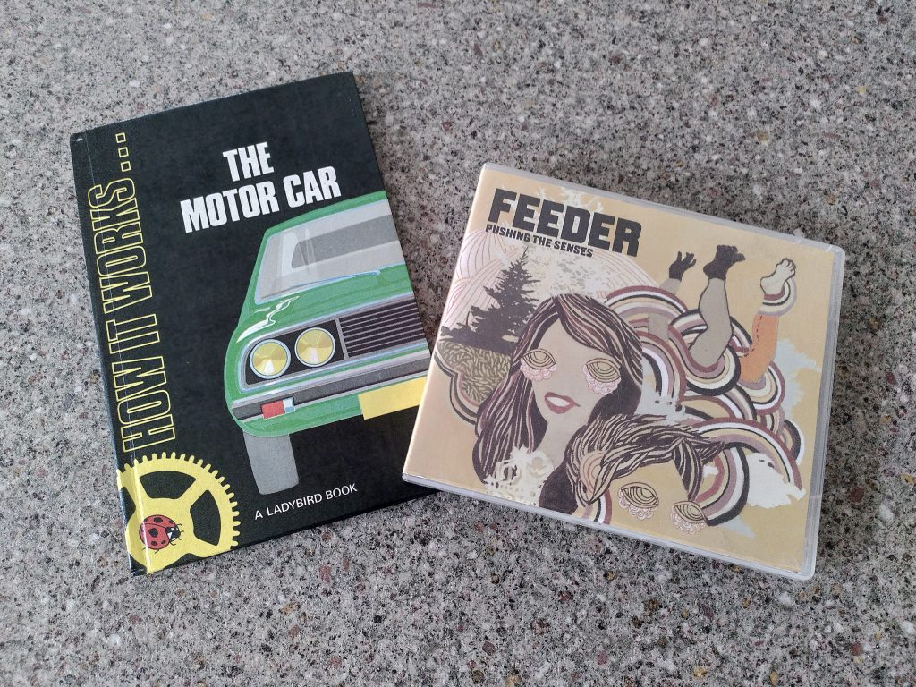 Photo of an old Ladybirds book called "How it works... The Motor Car", and a CD box of the album "Pushing the Senses" by Feeder.