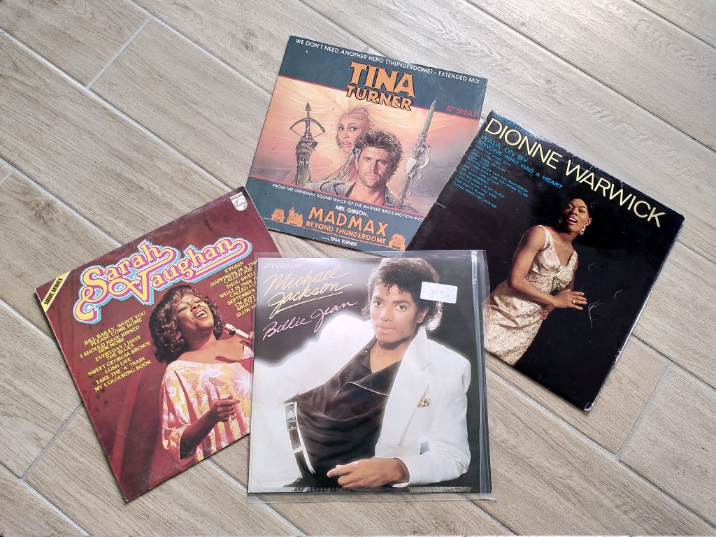 A selection of 4 12-inch vinyl records, including Mad Max Beyond Thunderdome, Billie Jean, Sarah Vaughan and Dionne Warwick.