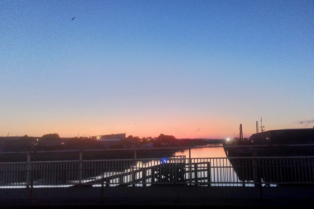 Photo of a blue and orange clear dusky sunset over the silhouette of a bridge, taken on the eve of solstice. Taken around 10pm.