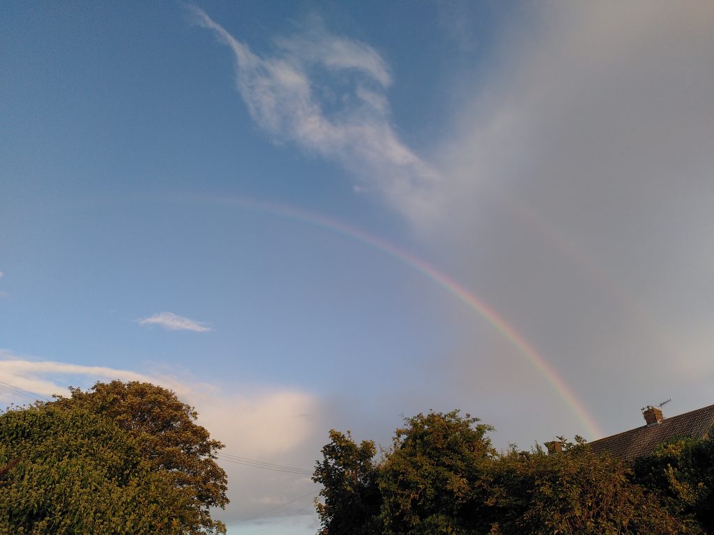 A rainbow reaching out into the blue sky.